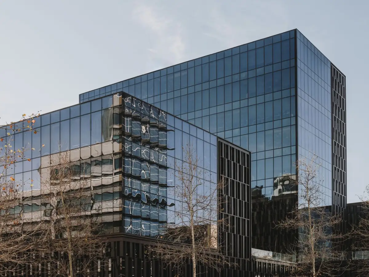 Glass towers of Platinum@BCN reflecting the neighbouring buildings, with leafless trees in the foreground