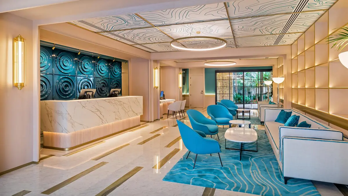 Hotel reception with a marble desk, a blue ceramic mural and a rug with a wave pattern