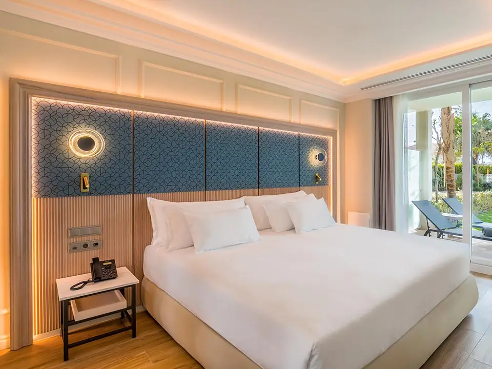 Room with a wooden headboard and blue patterned fabric, classical mouldings and access to the garden