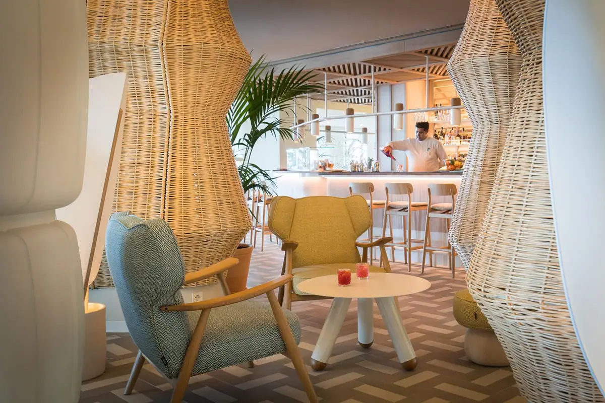 Lobby bar with wicker-clad columns, upholstered armchairs and a low white table