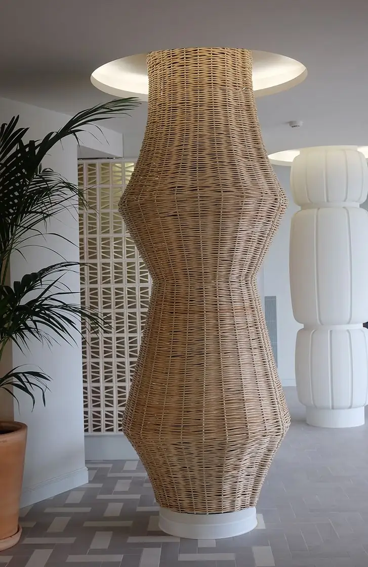 Column clad in woven wicker beside a ceramic screen and a white plaster column