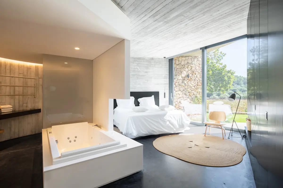 Villa bedroom with a whirlpool bath, exposed concrete and a window onto the garden