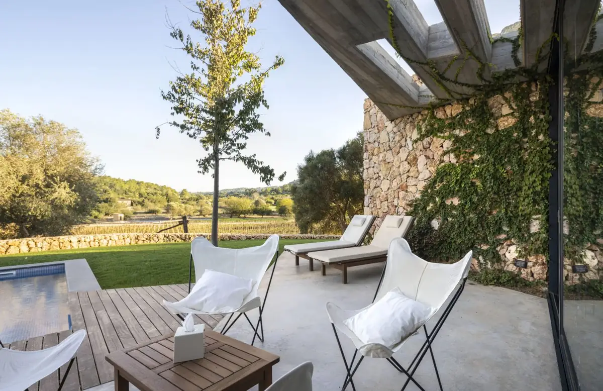 Terrace with butterfly chairs beside a stone wall covered in planting