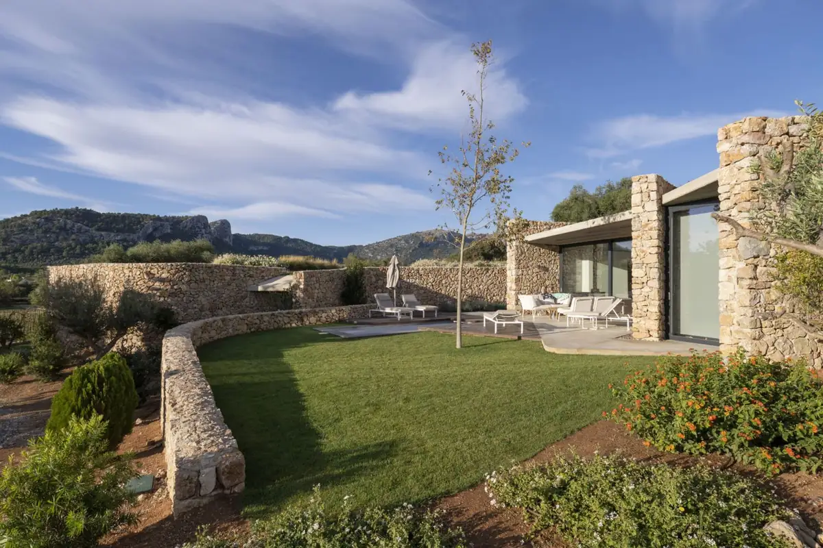 Villa garden with a curved dry-stone wall and a glazed façade