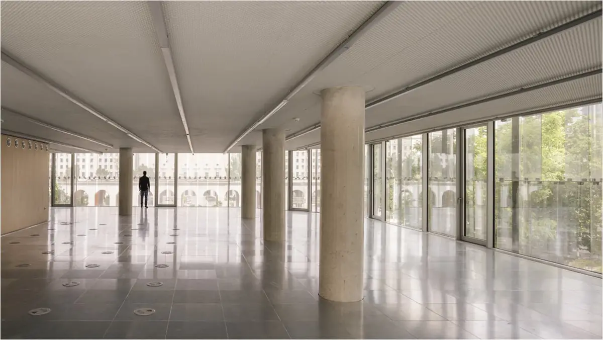 Planta de oficinas diáfana con pilares de hormigón, techo radiante visto y fachada acristalada