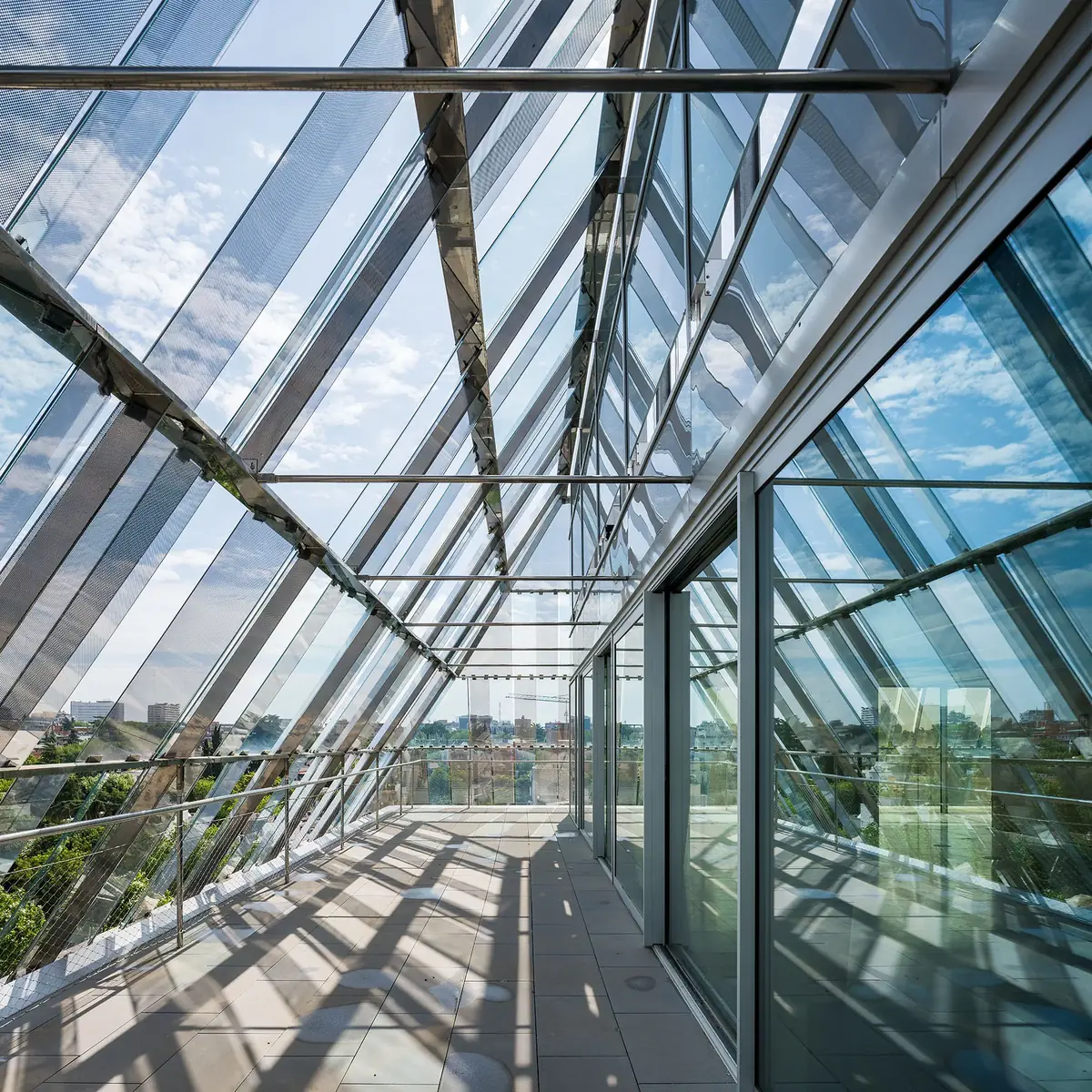 Pasarela exterior de la última planta bajo las lamas de vidrio inclinadas de la fachada