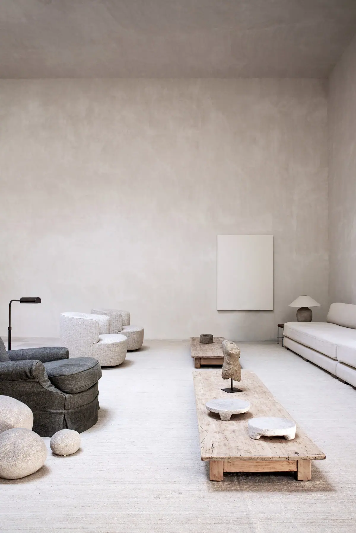 Seating area with pale sofas, armchairs, wooden coffee tables and stones on a fibre rug
