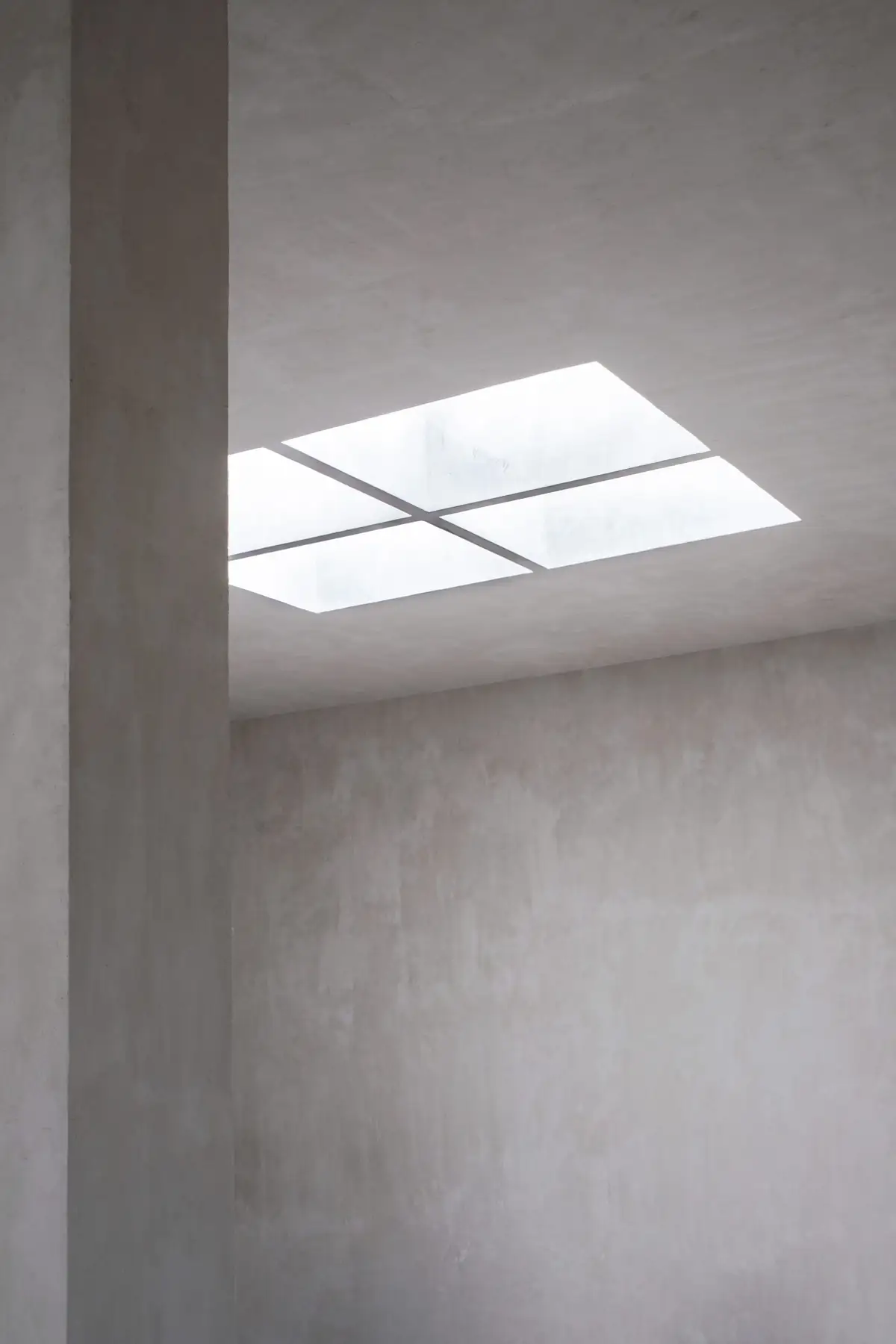 Square skylight in the ceiling of a double-height volume with lime walls