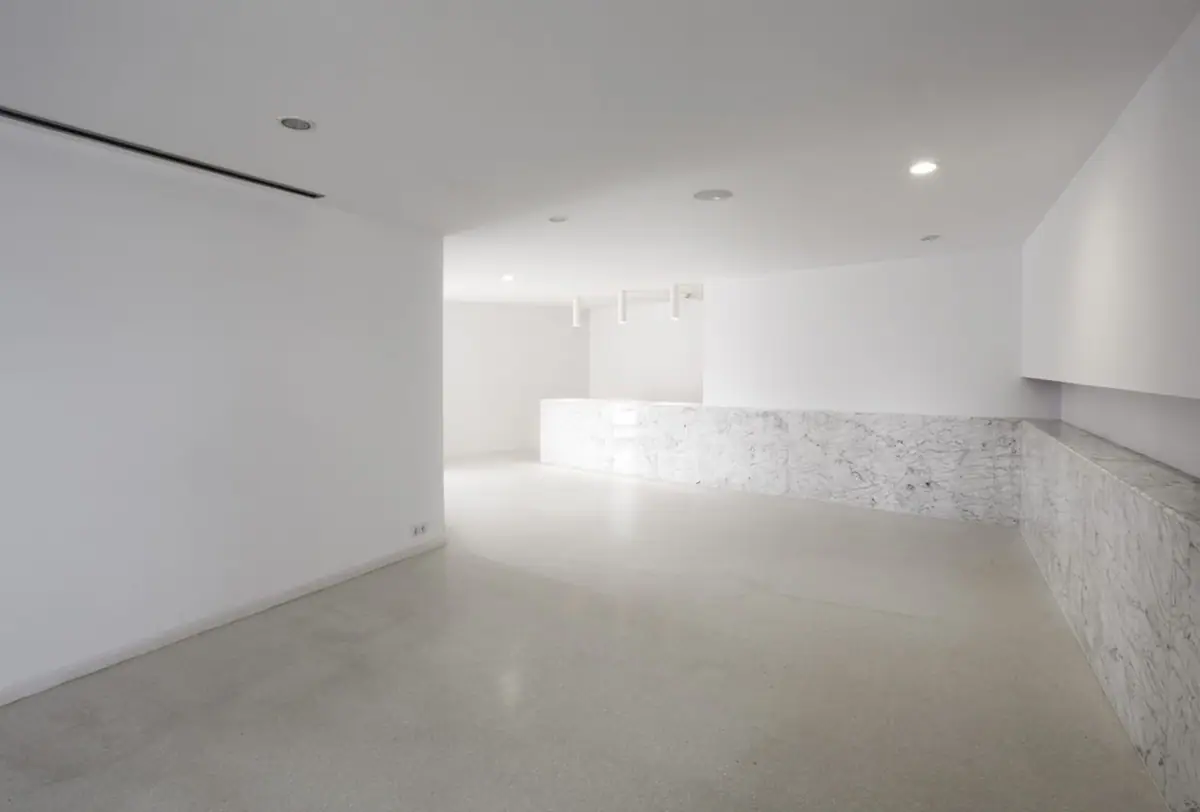 White interior space with a pale floor and a counter clad in veined marble