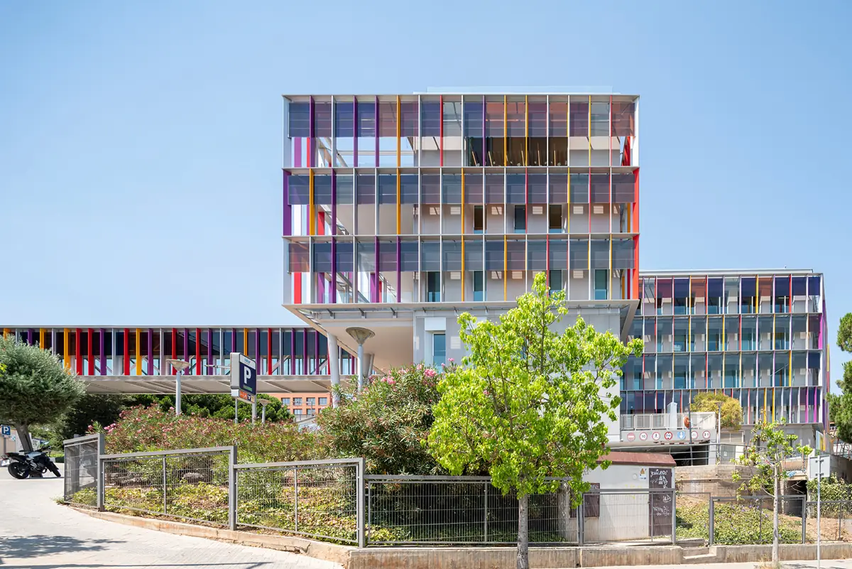 Vista exterior del centro terminado con la celosía de lamas de colores y la pasarela