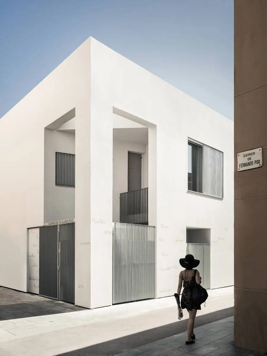 White corner with a large void, metal-slatted doors and the Fernando Poo street sign