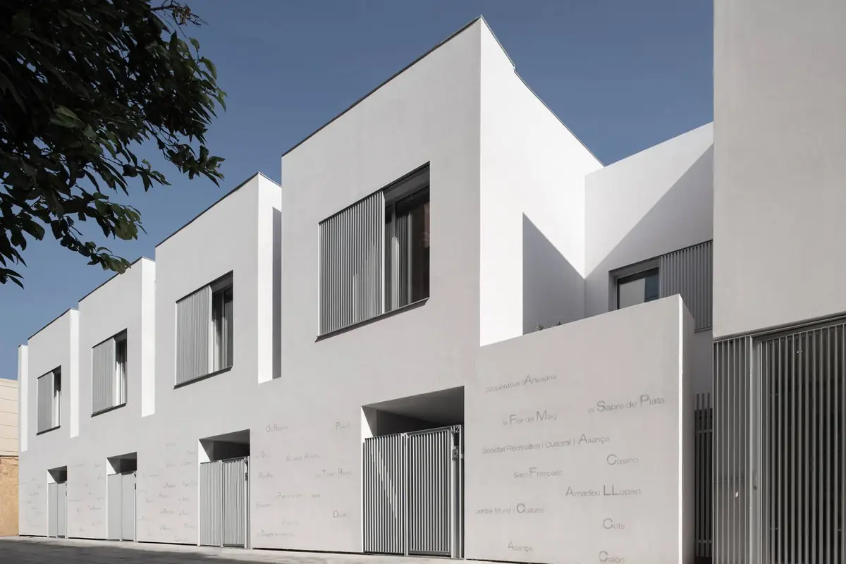 Row of white two-storey houses with screens and names painted on the ground-floor wall