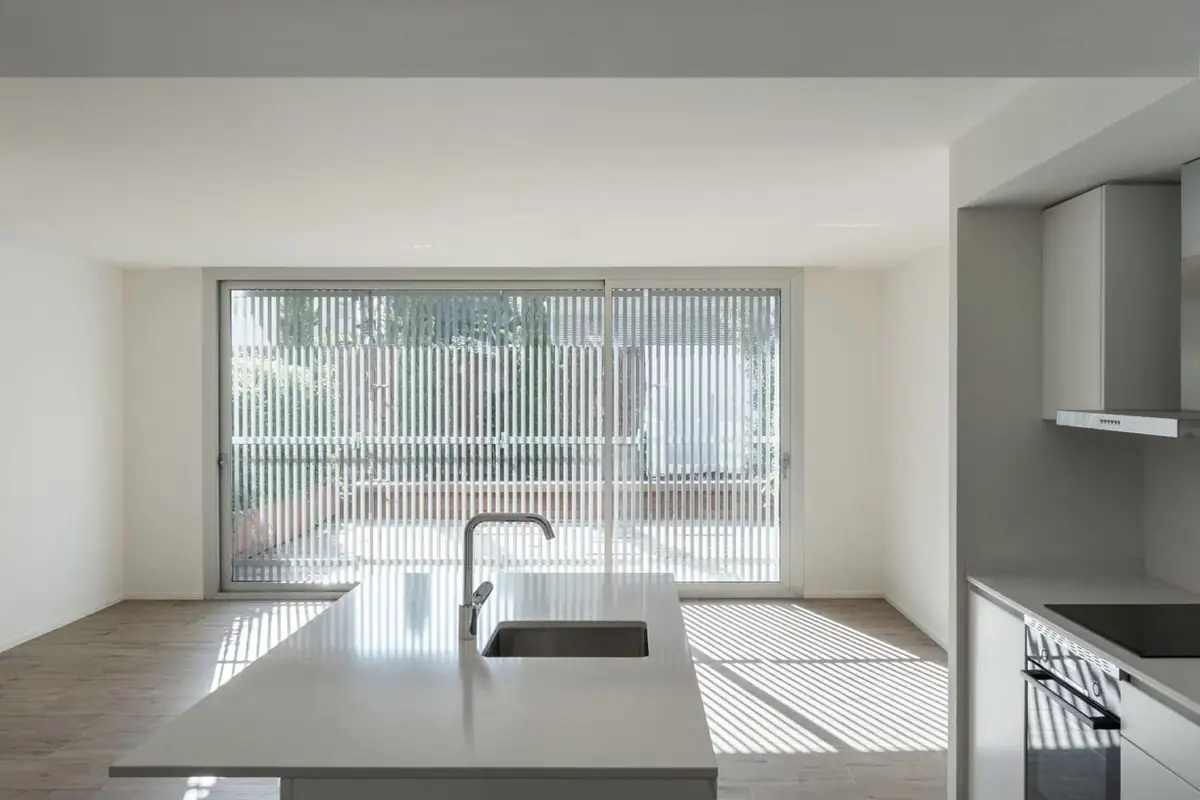 Open kitchen with a white island and a large sliding window screened by slats