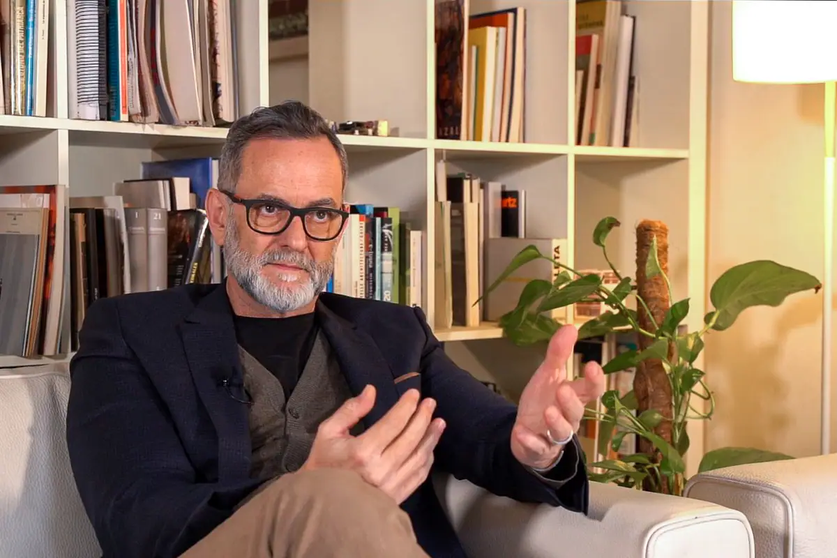 Retrato de Miquel Lacasta durante la entrevista, gesticulando ante una estantería de libros