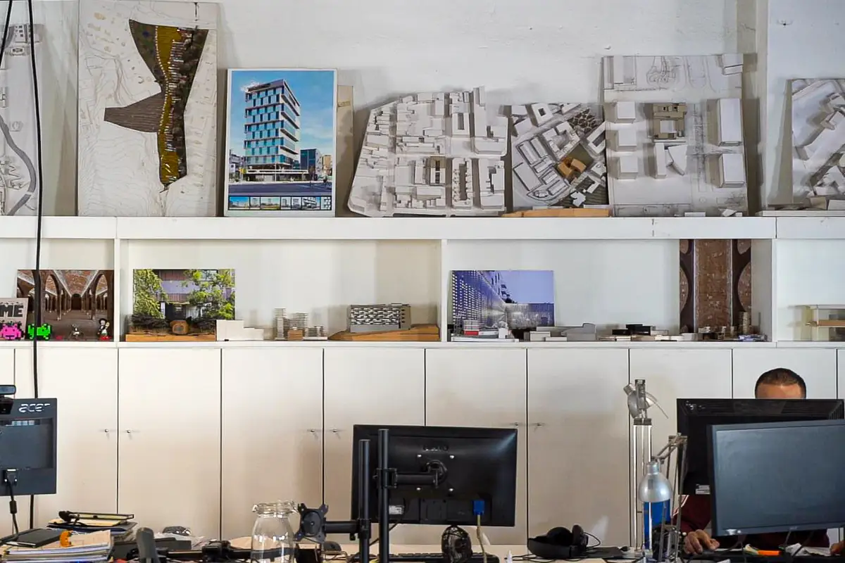 Estanterías con maquetas blancas, fotografías de proyectos y puestos de trabajo en el estudio