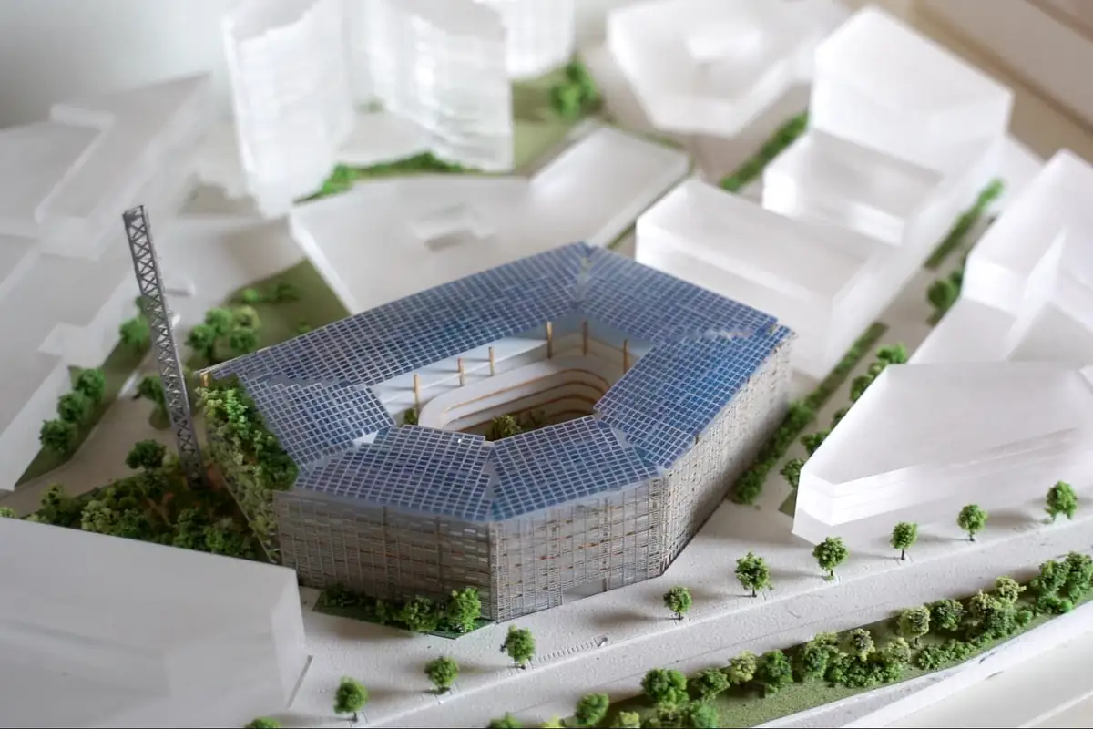 Maqueta de un edificio con cubierta de paneles solares y patio central entre volúmenes blancos y arbolado