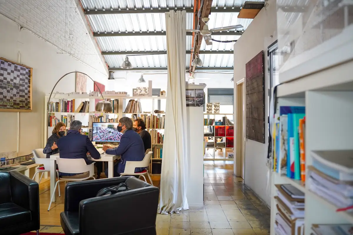Zona de reuniones del estudio con estanterías, sillones y una cortina que separa los espacios