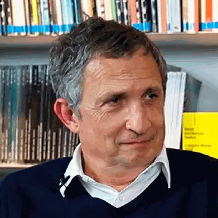 Portrait of Enric Batlle during the interview, in front of a shelf of architecture magazines