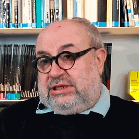 Portrait of Joan Roig during the interview, wearing round glasses, in front of a bookcase