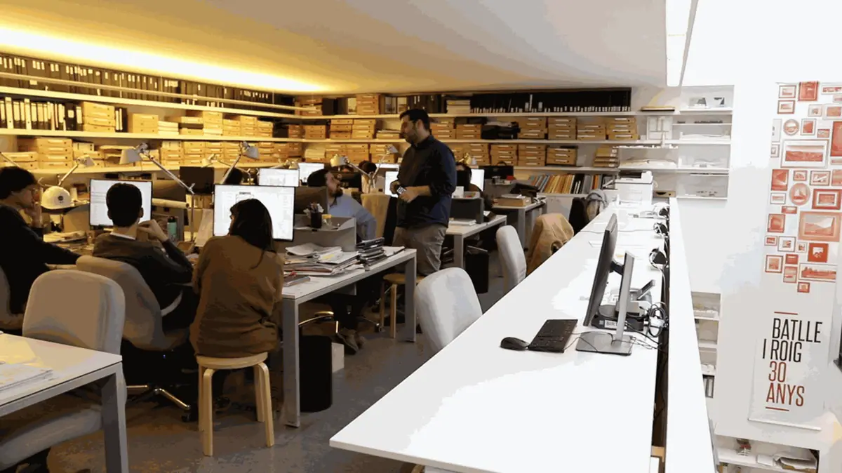 Team at work on the studio floor, with files on the shelves and a poster marking Batlle i Roig's 30 years