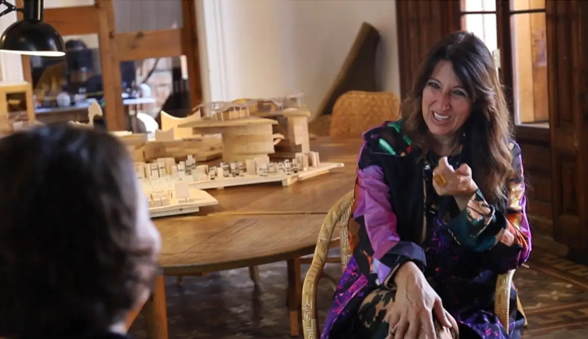 Benedetta Tagliabue talks, seated at a table with wooden models