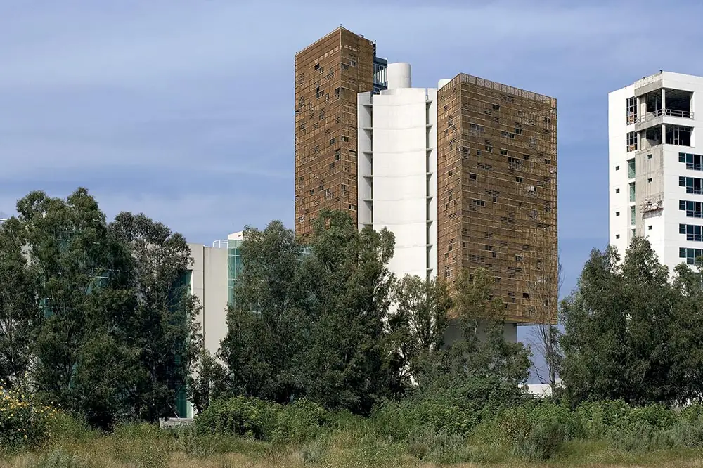 Cube office tower with a timber lattice façade among trees in Guadalajara