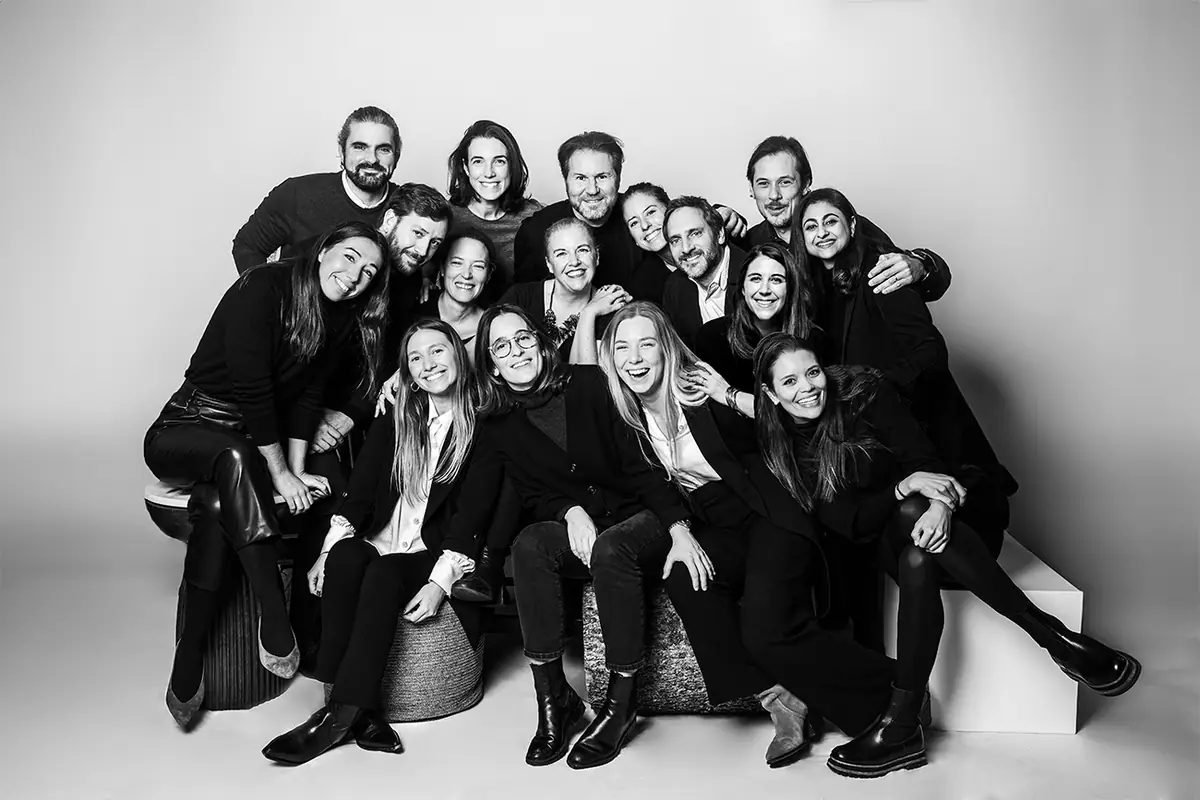 Black-and-white portrait of the Gronda team, smiling and grouped on stools in a photographic studio