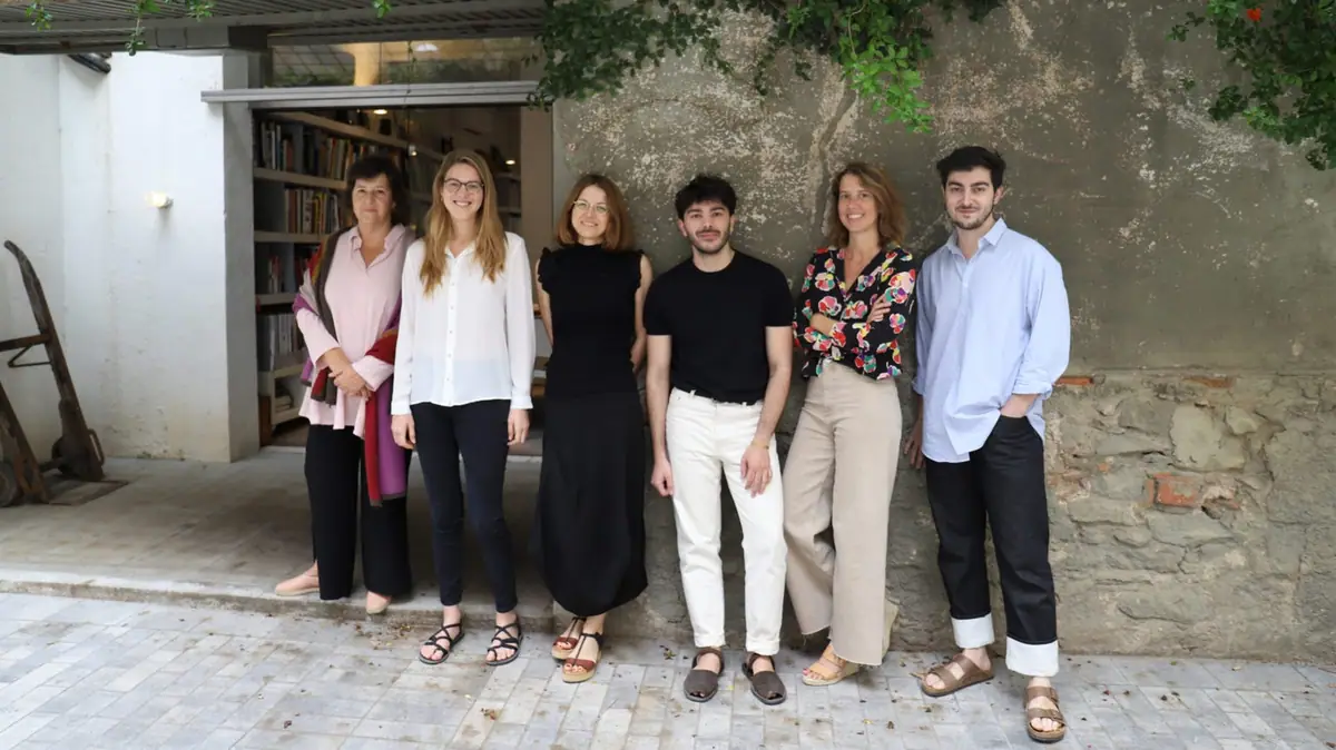 Isabel López Vilalta and five members of her team pose in front of a stone wall by the studio entrance