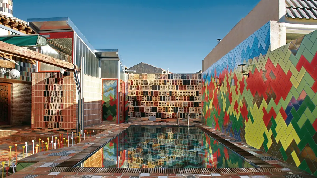 Patio con piscina rodeado de muros de ladrillo perforado y de cerámica de colores colocada en espiga