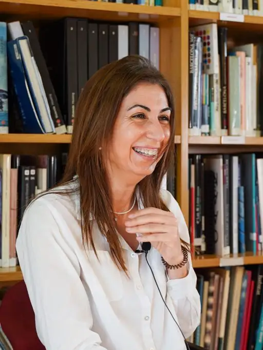 Sonia Sanz ríe durante la entrevista, frente a una estantería de libros de arquitectura