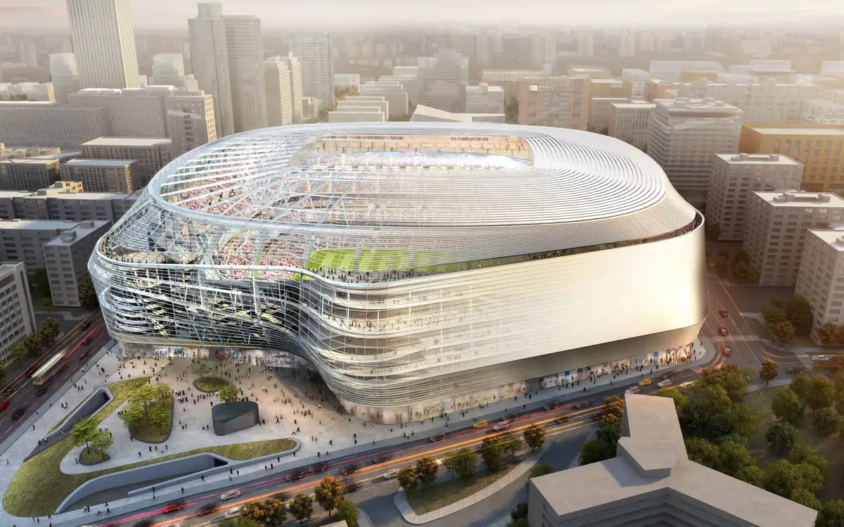 Vista aérea del estadio Santiago Bernabéu remodelado, con su envolvente metálica curva y una plaza peatonal ante el estadio