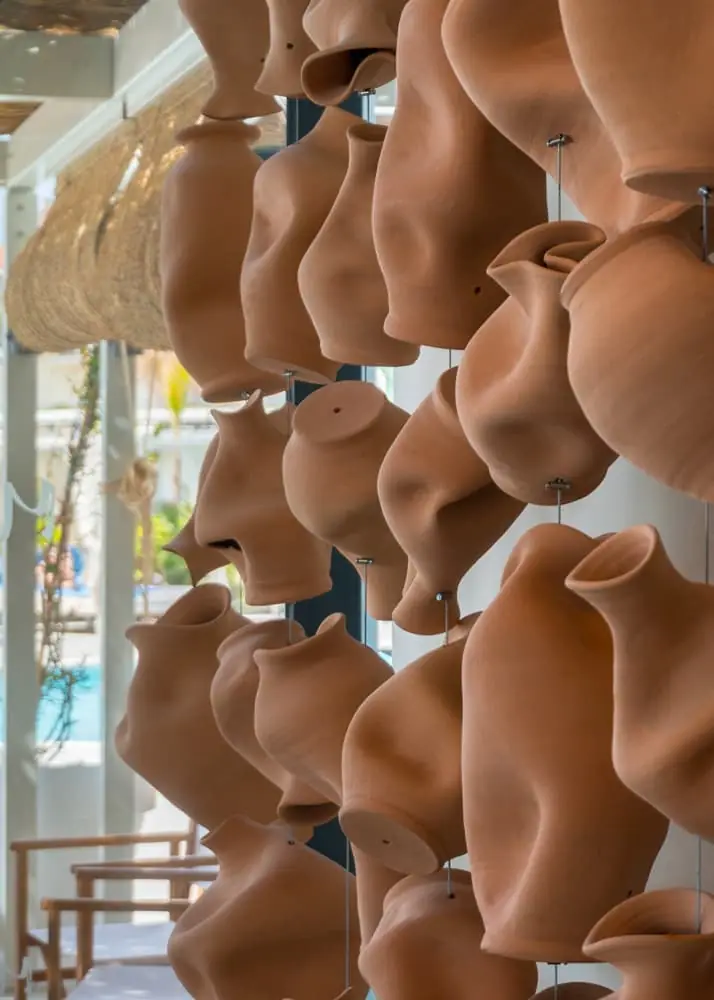 Biombo formado por jarrones de terracota deformados, colgados en hileras con cables metálicos