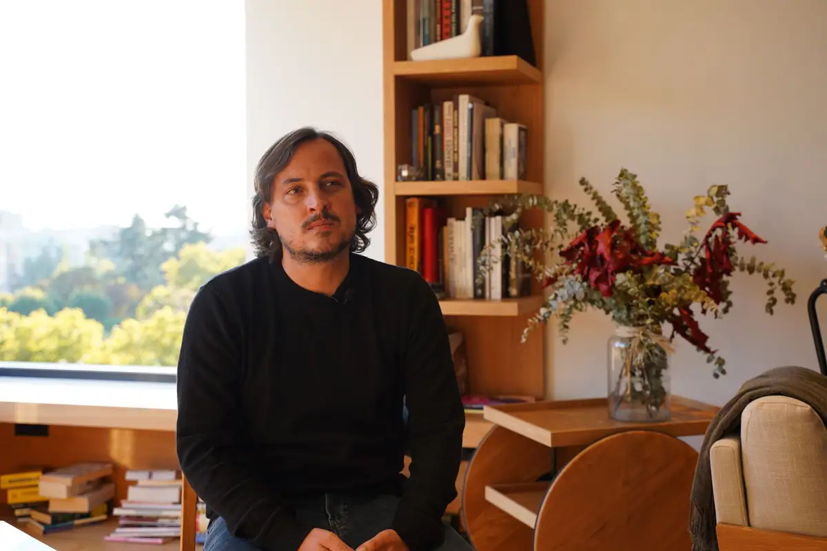 Uno de los socios de Zooco Estudio, sentado junto a una estantería de roble y un ventanal, durante la entrevista
